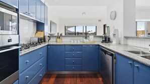 Una cocina moderna con armarios azules, encimera de granito y electrodomésticos de acero inoxidable.