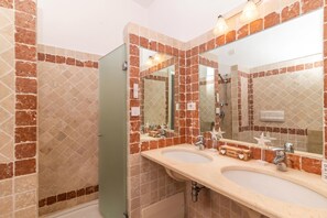 Une salle de bain avec deux lavabos, un miroir et une douche.