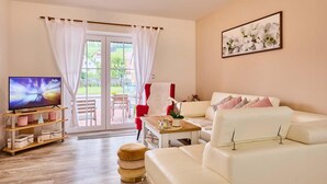 A living room with a TV, a red chair, a white sofa, and a wooden coffee table. - Chalupa Gita in Svoboda nad pou (Svoboda nad Upou)