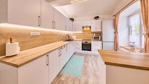 A modern kitchen with white cabinets, a wooden countertop, a built-in oven, and a microwave. - Chalupa Gita in Svoboda nad pou (Svoboda nad Upou)