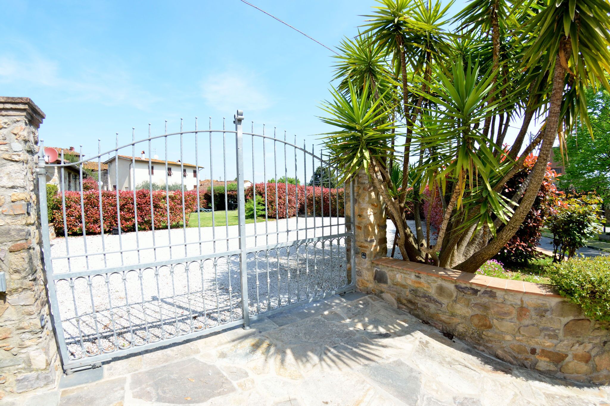 A gated entrance with a stone wall and a metal gate.