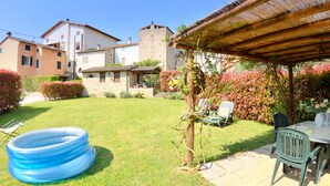 A backyard with a blue inflatable pool, a pergola, and a table with chairs.
