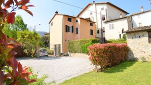 A two-story building with a gravel driveway and a stone wall.