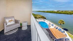 A balcony with a view of a river, a pool area with lounge chairs, and a dining area. - Waterfront! Tennis/Pickleball, Pool, Grill Area, GOLF, BEACH,FUN FREE TICKETS Incl 509 Bayshores (Indian Shores)
