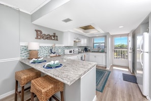 A kitchen with a central island, white cabinets, a microwave, and a refrigerator. - Waterfront! Walk to Beach -  509 Bayshores (Indian Shores)