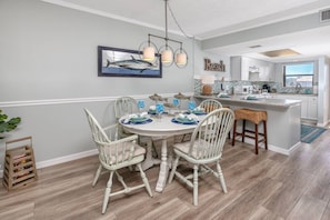 A dining area with a round table, white chairs, and a chandelier.