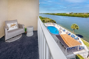 A balcony with a view of a river, a pool, and outdoor seating. - Waterfront! Walk to Beach -  509 Bayshores (Indian Shores)