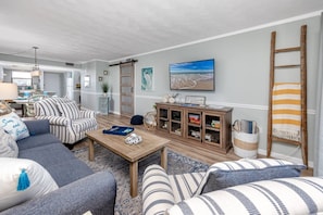 A living room with a sofa, armchair, coffee table, and a cabinet with decorative items. - Waterfront! Walk to Beach -  509 Bayshores (Indian Shores)