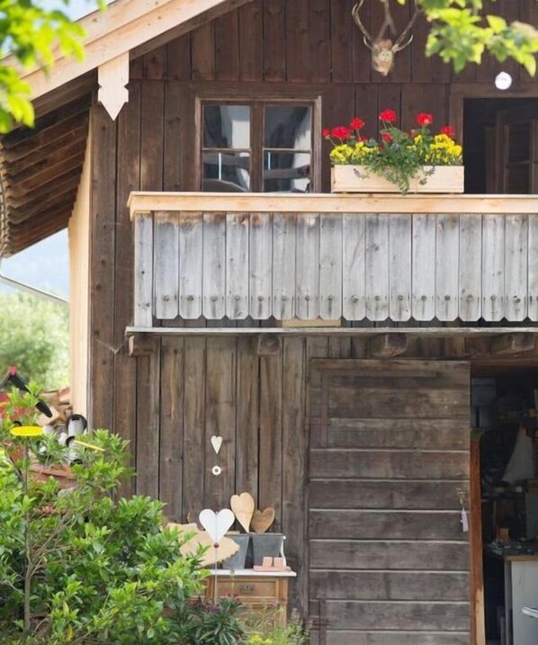 A rustic wooden building with a balcony, a flower box, and a deer head decoration.