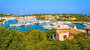 A marina with numerous boats docked, surrounded by buildings and greenery. - CDT Cala Del Faro (Arzachena)