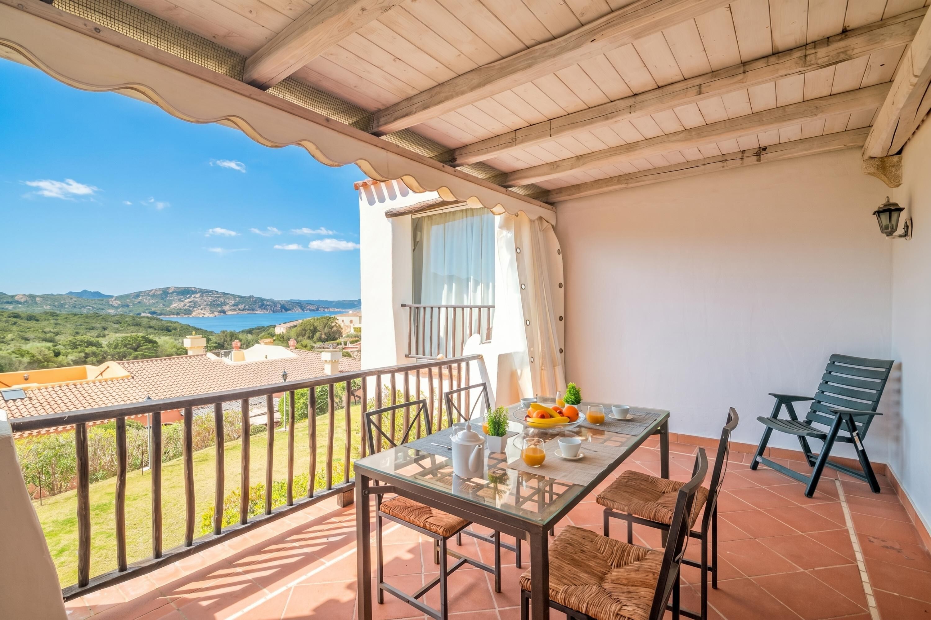 A balcony with a table set for breakfast, a chair, and a view of the countryside.