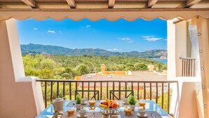 A balcony with a table set for breakfast, overlooking a mountainous landscape. - CDT Cala Del Faro (Arzachena)