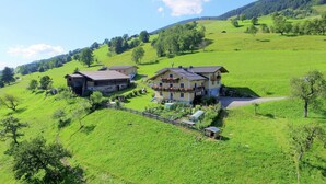 Una casa grande con balcón, rodeada por un campo verde y una cerca.