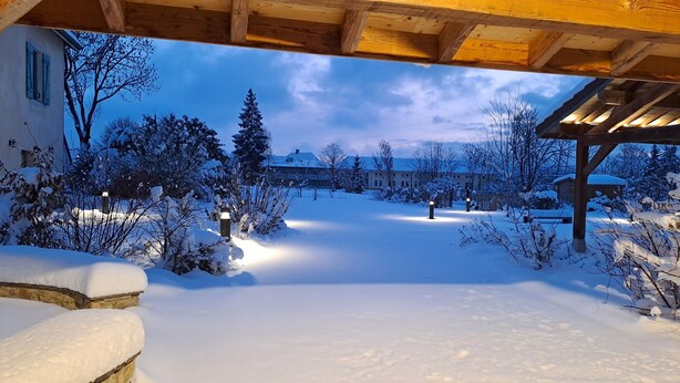 A snow-covered outdoor area with a wooden pergola and snow-covered trees.