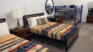 A hotel room with a large bed, a smaller bed, a nightstand with a lamp, a dresser, and a mirror on the wall.