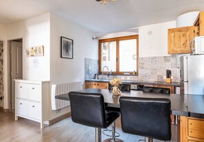 A modern kitchen with a central island, wooden cabinets, and a window. - L ISLE PERRIERE - Room - Balcony - View of the Palais de l'&Icirc;le (Annecy)