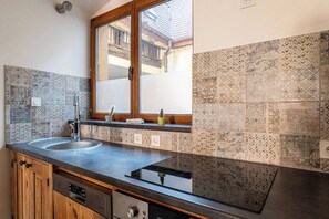 A kitchen with a double sink, wooden cabinets, a window with a view, and patterned tiles.
