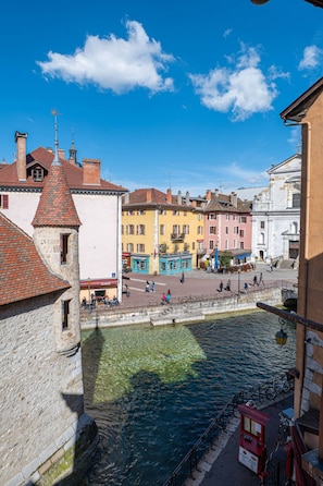 A historic town with a canal, stone buildings, and a clear blue sky.