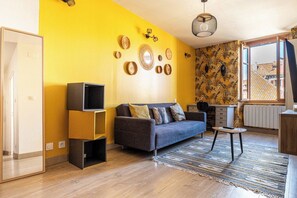 A living room with a sofa, a coffee table, and a TV stand. - L ISLE PERRIERE - Room - Balcony - View of the Palais de l'&Icirc;le (Annecy)