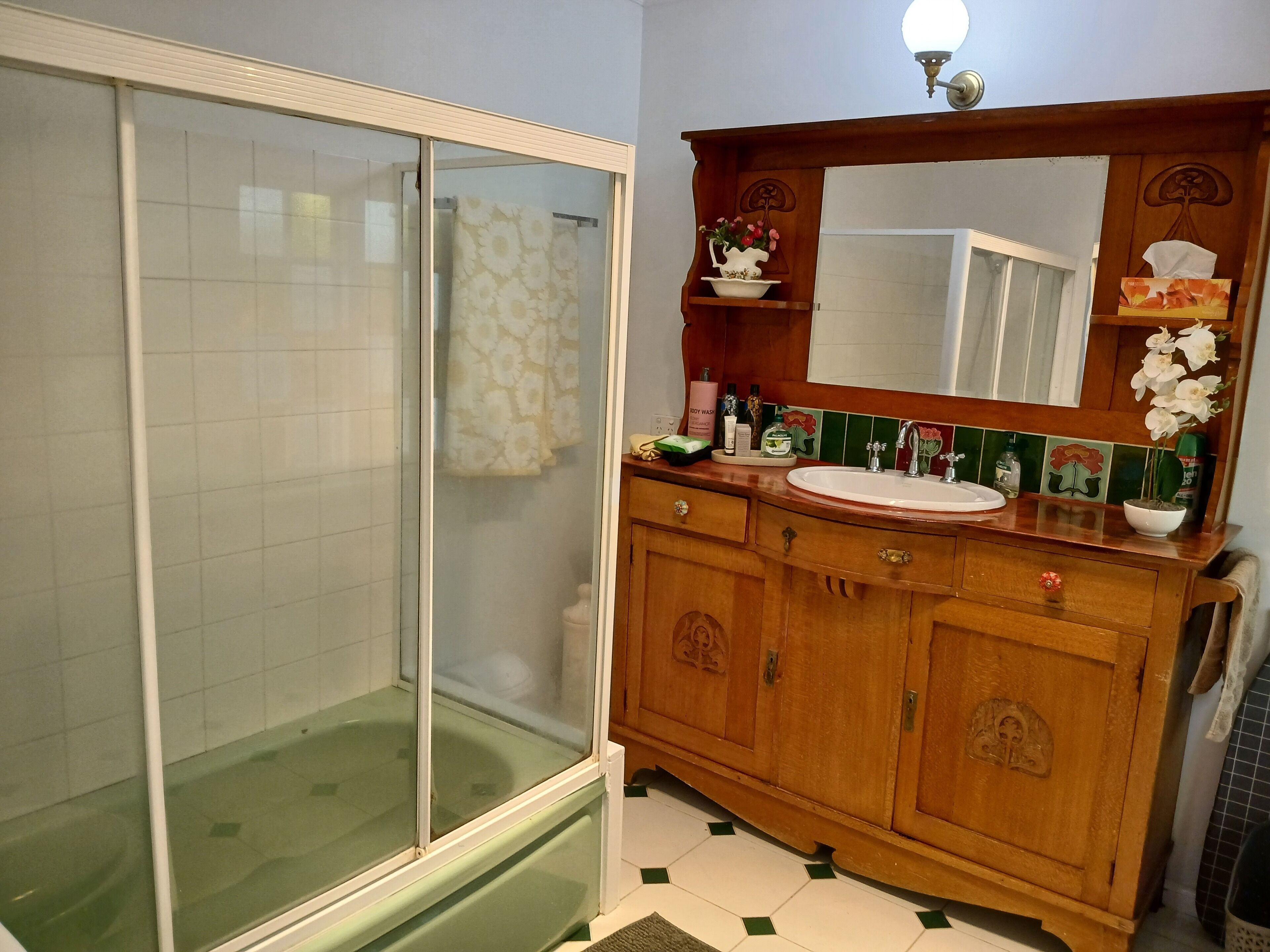 Une salle de bain avec une douche à parois de verre, un meuble-lavabo en bois et un miroir au-dessus.