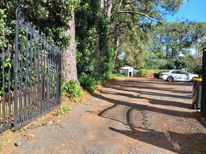 A gated driveway leading to a building with a small garage and a parked car. - Memory Lane Accommodation (Tamborine Mountain)