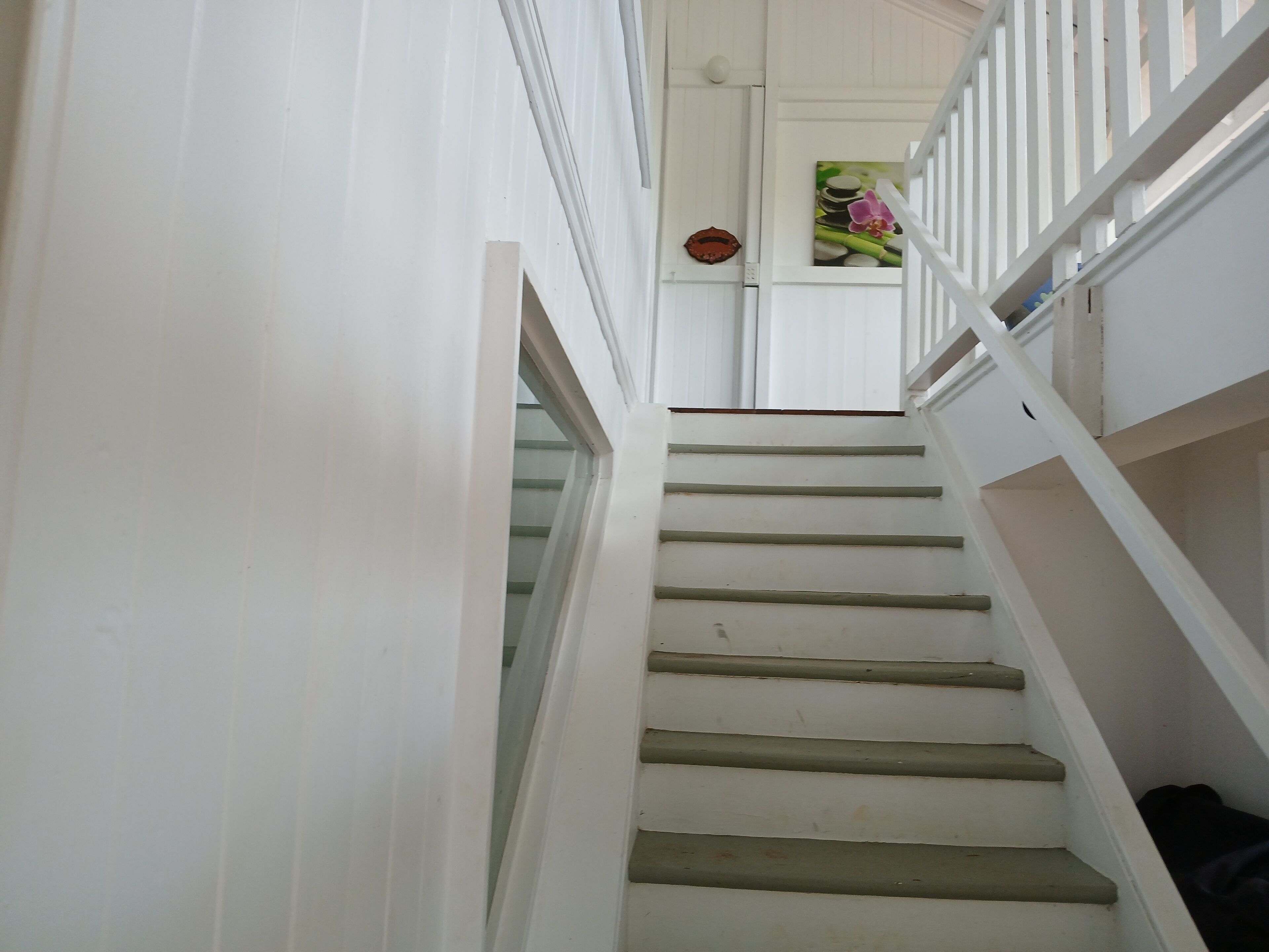 A staircase with white railings and steps, leading to a landing with a door and a wall-mounted decorative item.