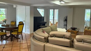 A spacious living room with a curved sectional sofa, a dining table with chairs, and a fireplace. - Memory Lane Accommodation (Tamborine Mountain)