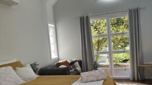 A bedroom with a large bed, a skylight, a view of greenery outside, and a modern chandelier. - Memory Lane Accommodation (Tamborine Mountain)