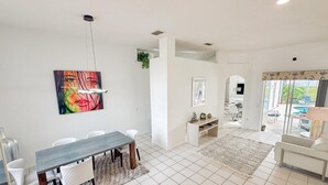 Ett modernt vardagsrum med en matplats, en TV och utsikt över omgivningarna.
