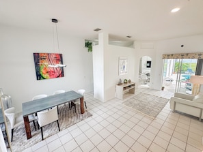 Una sala de estar moderna con comedor, televisor y vistas al exterior.