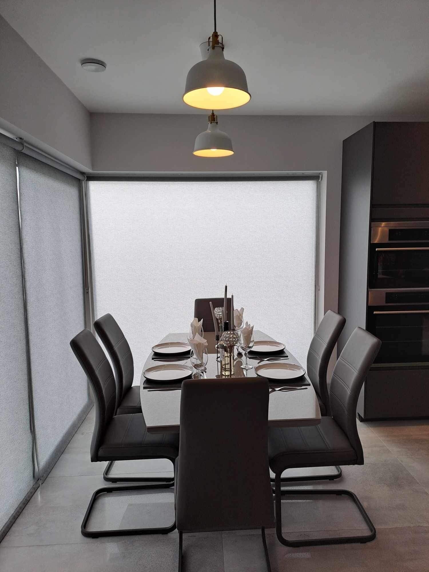 Een moderne eetruimte met een tafel voor vier personen, zwarte stoelen en een hanglamp erboven.