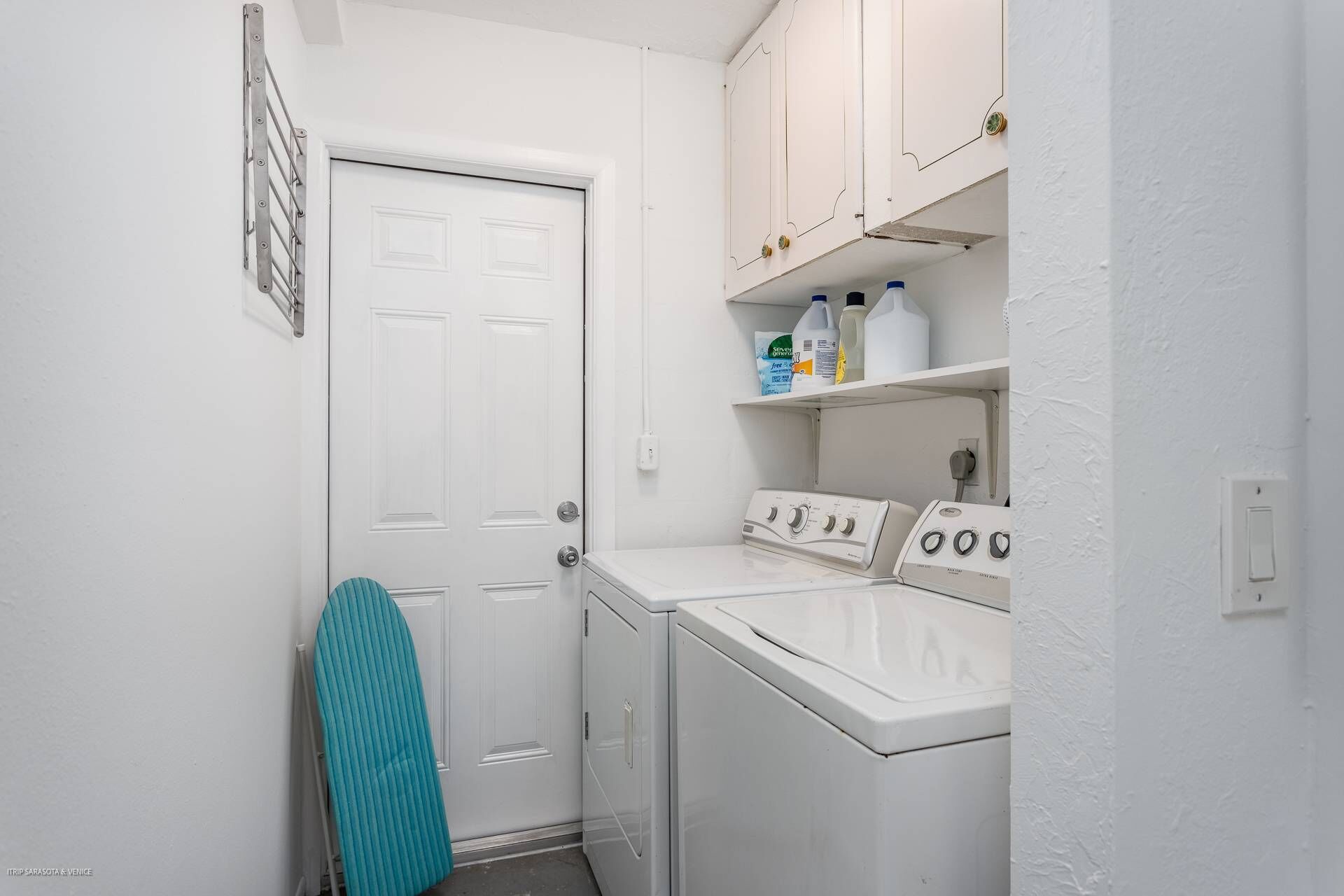 A laundry room with a washing machine, dryer, and shelves with cleaning supplies.