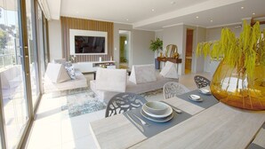 A modern living room with a sofa set, a dining table with plates and cutlery, and a large window. - Azalia Apartments (Sandton)