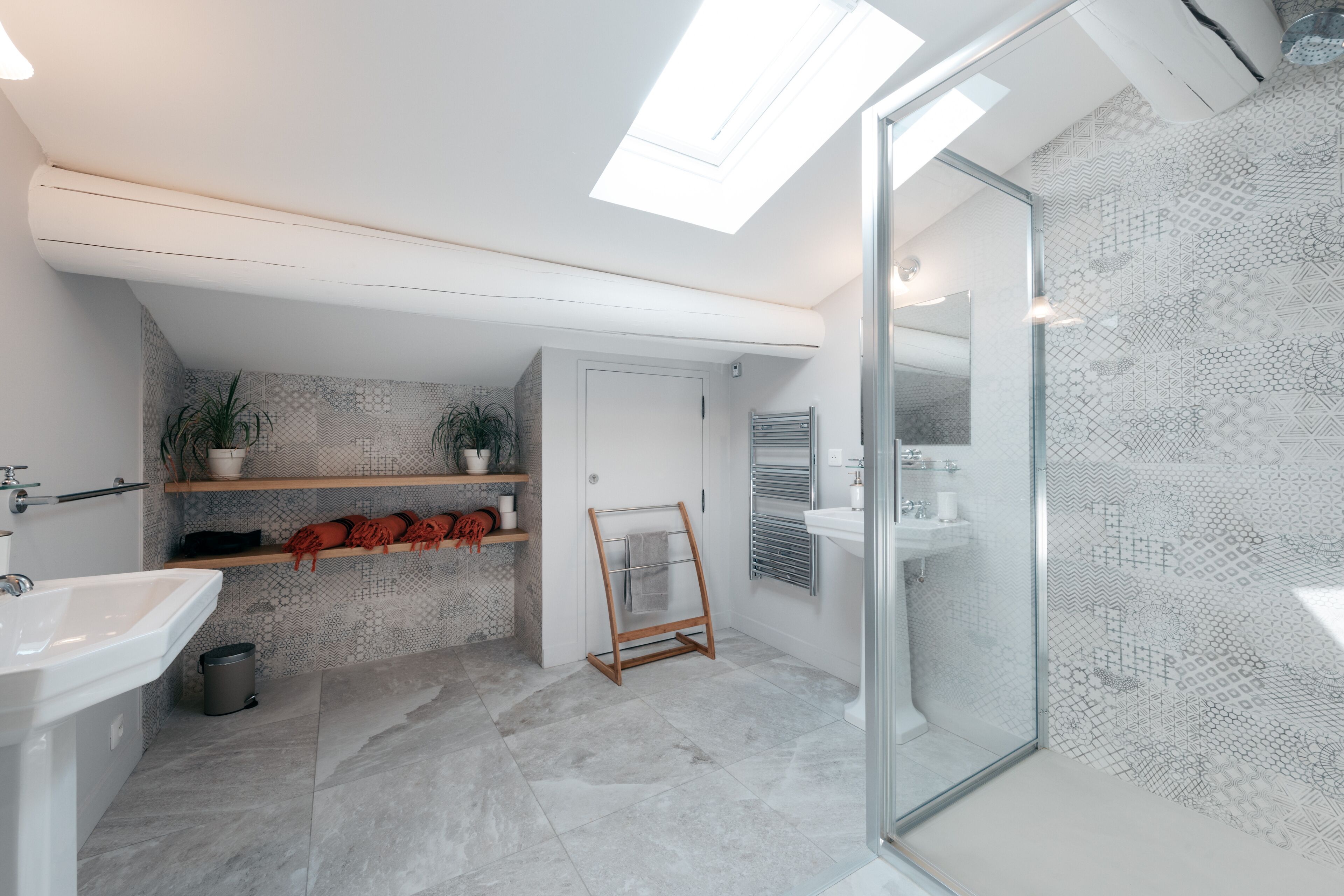 Un baño moderno con tragaluz, ducha e lavamanos.