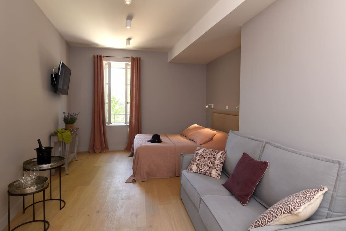 Uma sala de estar moderna com sofá, uma mesinha, TV fixada na parede e uma janela com cortinas.