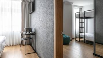 A modern room with a wooden floor, a desk with a chair, a bunk bed, and a grey textured wall.