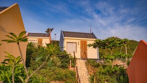 A two-story house with a stone staircase leading to the entrance, surrounded by lush greenery and a clear sky. -  Life Resort Quy Nhon (Cat Tien)