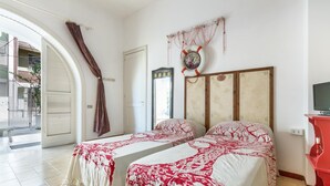 A room with two beds, a mirror, a clock, and a red cabinet. - 3821 VBR - Mono Rosa by Barbarhouse (Porto Cesareo)