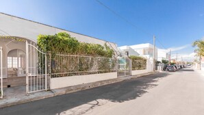 A quiet street with a white building, a gated entrance, and parked cars. - 3821 VBR - Mono Rosa by Barbarhouse (Porto Cesareo)