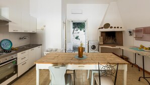 A compact kitchen with white cabinets, a wooden table, and a view of the outdoors through an open door. - 3821 VBR - Mono Rosa by Barbarhouse (Porto Cesareo)