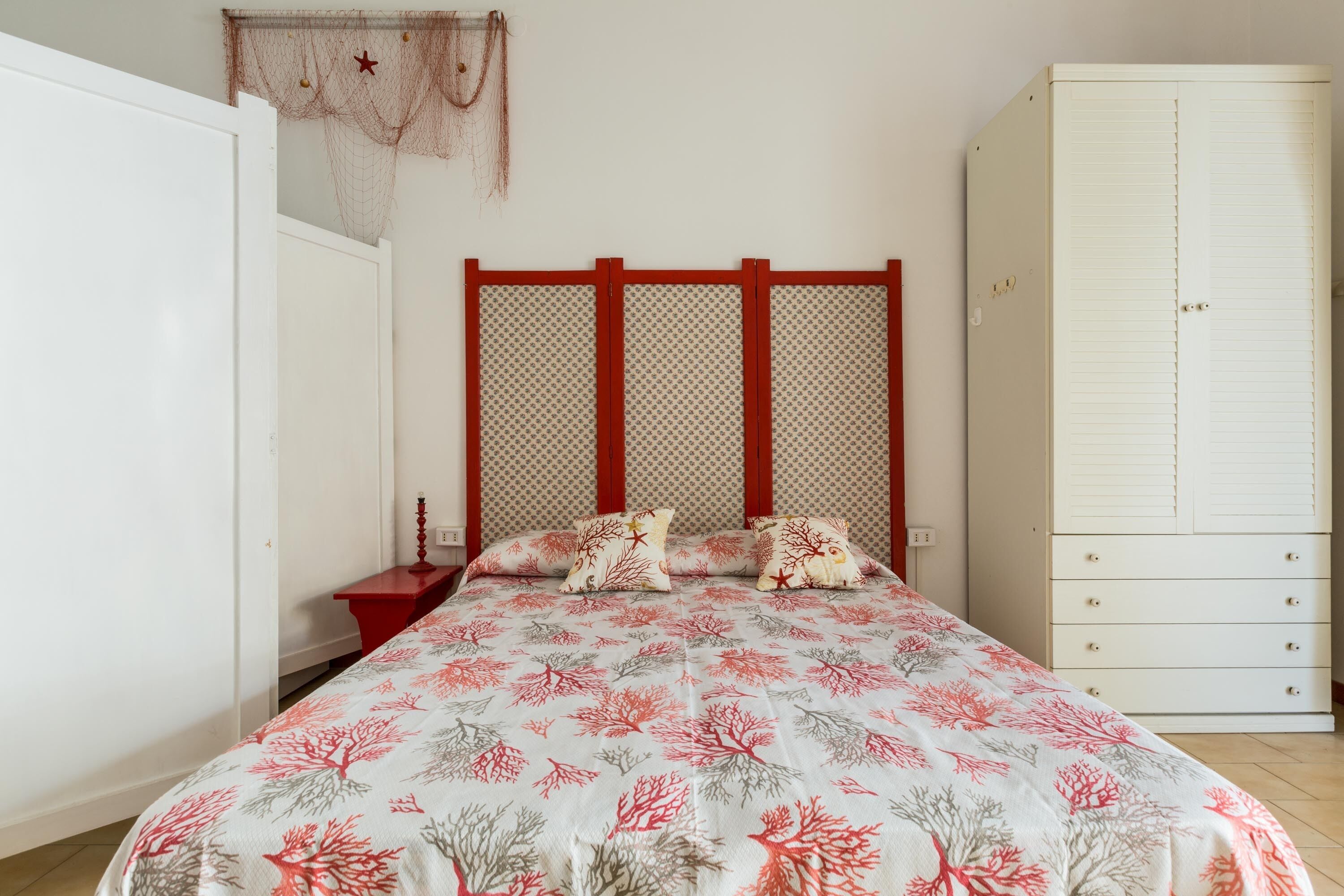 Un dormitorio con cama, mesita de noche, armario y un adorno colgante.