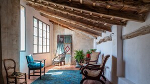 A rustic room with exposed wooden beams, a large window, and a hanging chair. - 7 Pisos Casa Rural de Pueblo (Cocentaina)