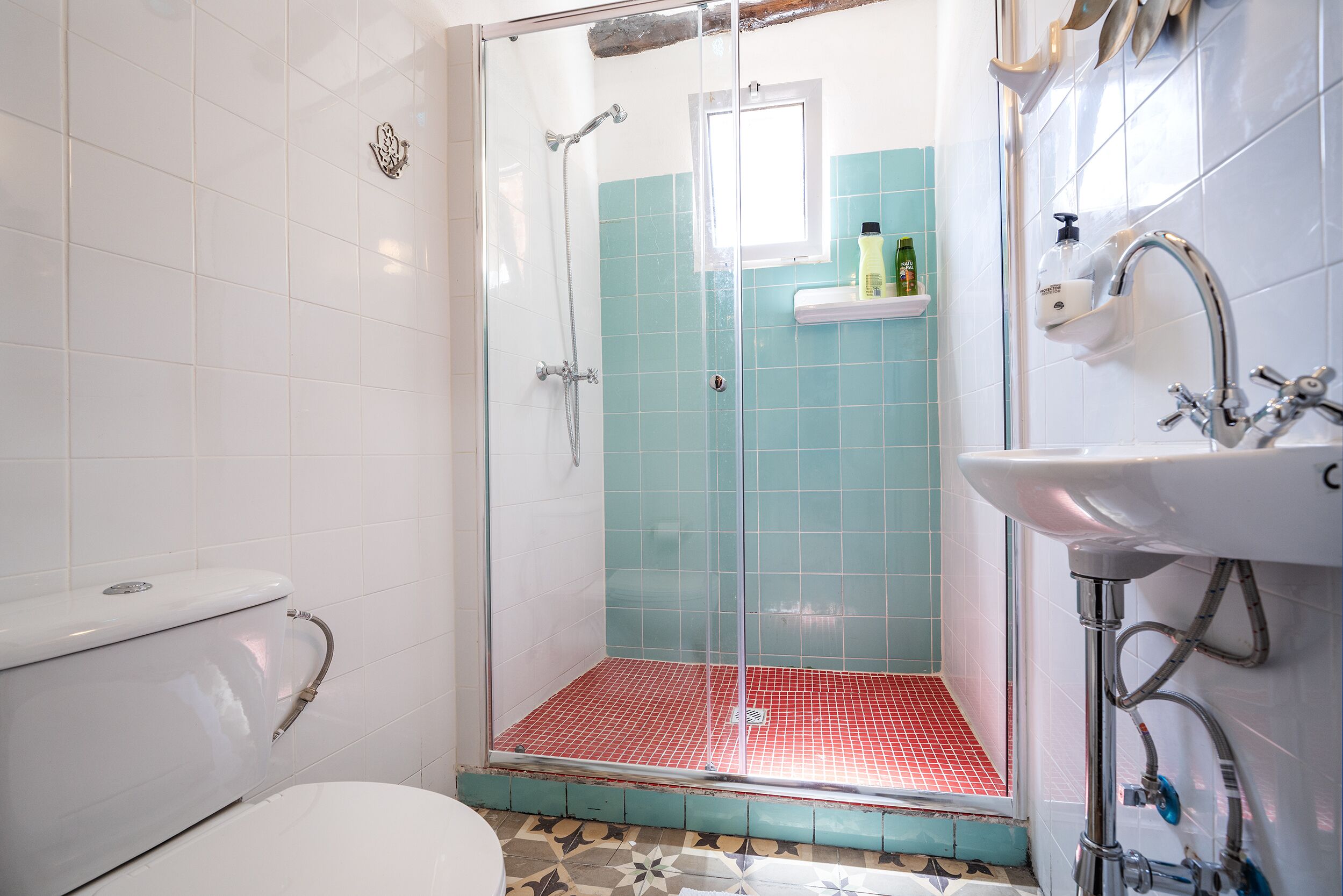 Un bany amb dutxa trencada per vidre, un vàter blanc i un lavabo amb mirall.