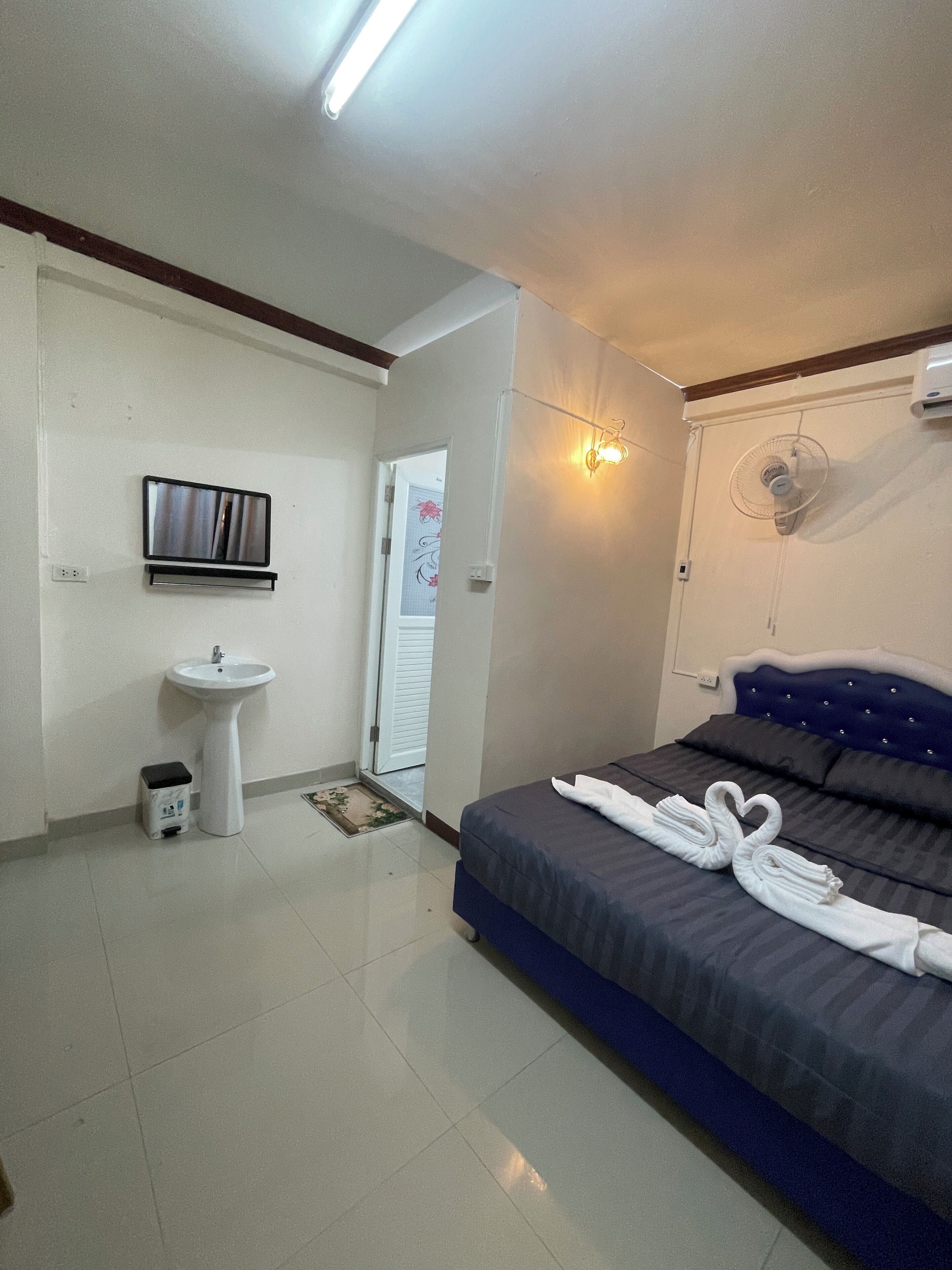 A hotel room with a bed, a bedside table, a sink, and a mirror.