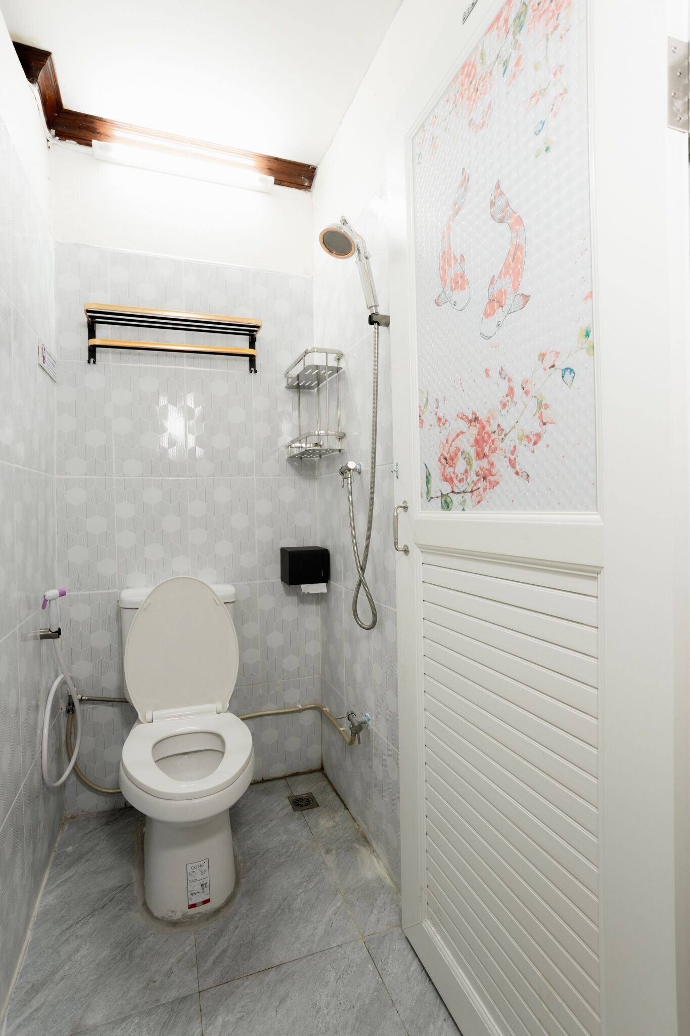 Un baño con inodoro, ducha y un revestimiento decorativo con motivos florales.