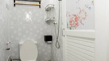 Un baño con inodoro, ducha y un revestimiento decorativo con motivos florales.