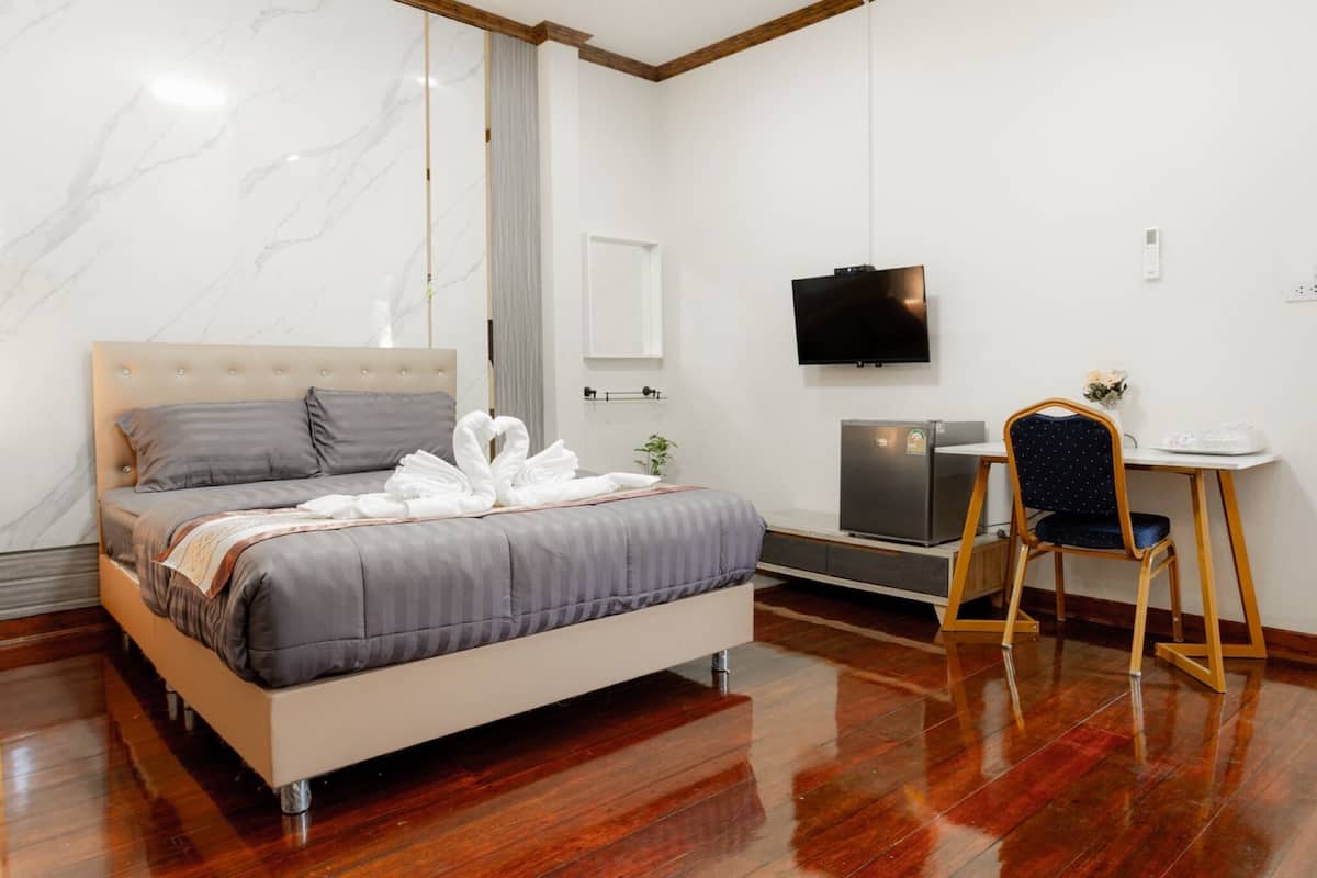 A modern hotel room with a bed, a desk, a TV, and a chair.