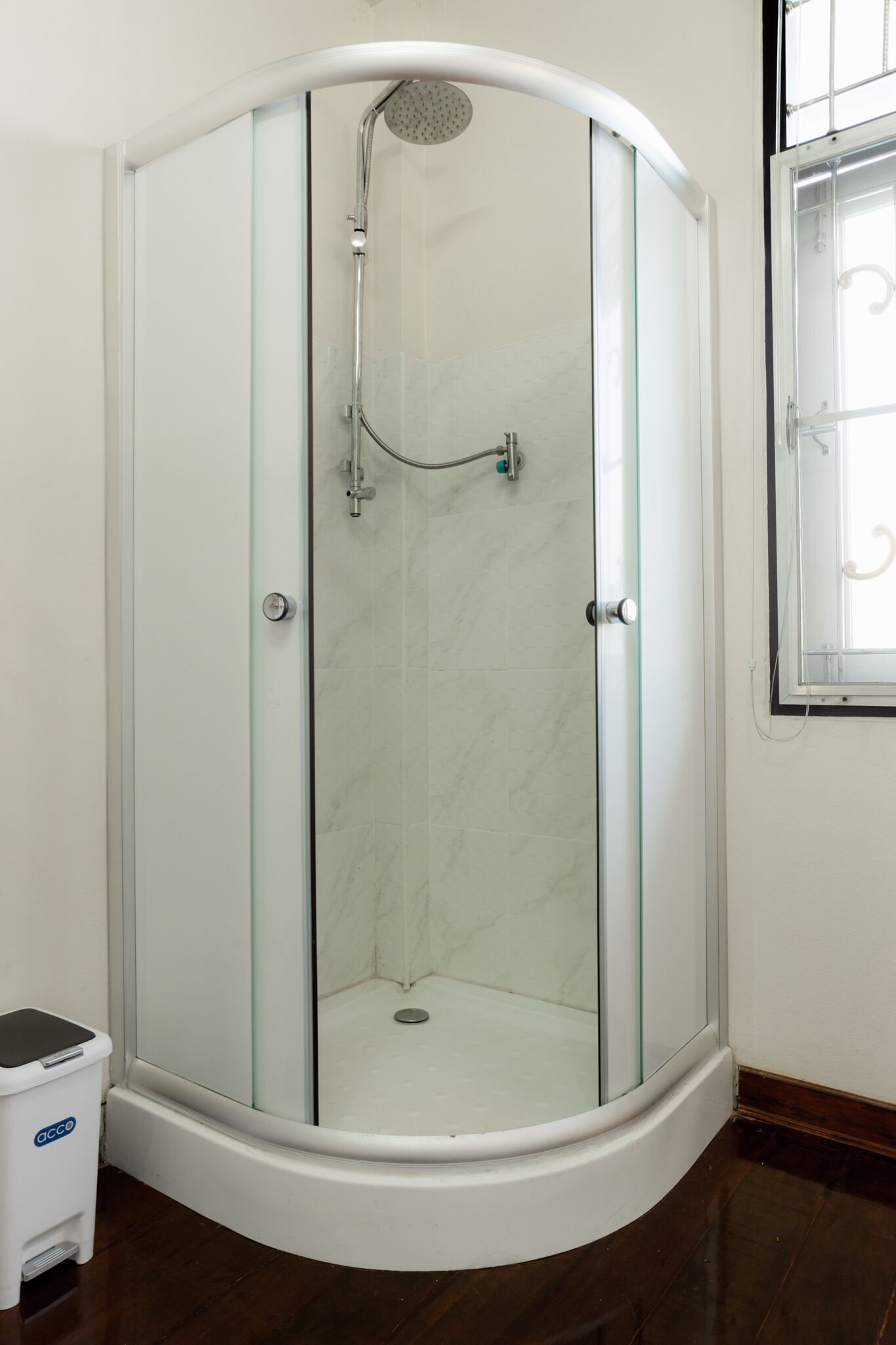 A glass-enclosed shower stall with a curved design, a showerhead, and a glass door.