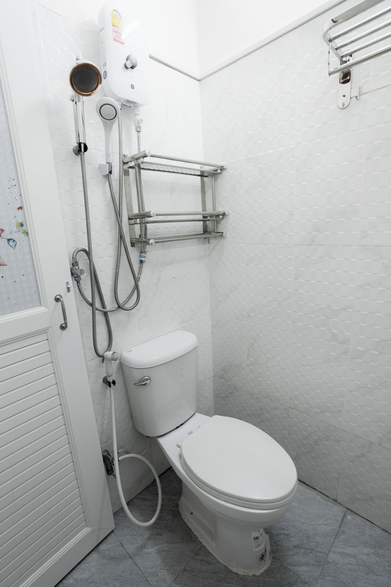 A bathroom with a toilet, a shower unit, and a towel rack.