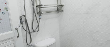 Un baño con inodoro, ducha y barra para toallas.